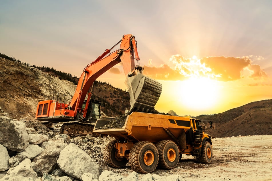 Excavator loading dumper truck on mining site